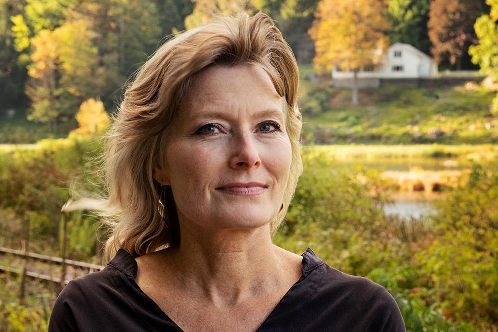 Headshot of author Jennifer Egan posed in front of a rural background.